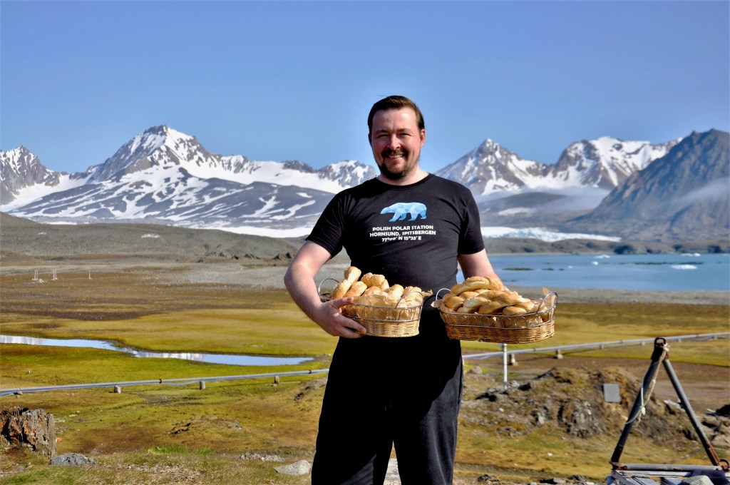 Man holding baskets with breads with mountains in the background 