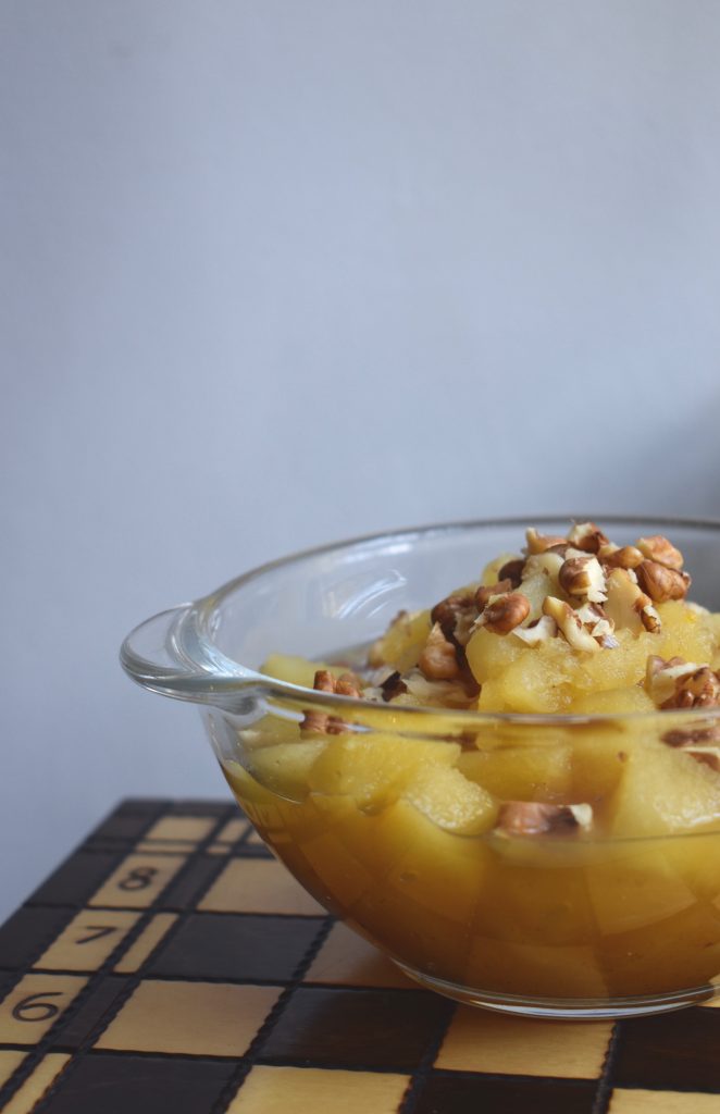 A bowl of apple compote with walnuts on a chessboard