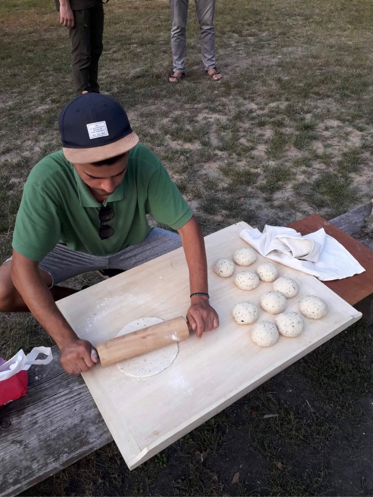 man rolling out pastry for flatbreads outdoors 