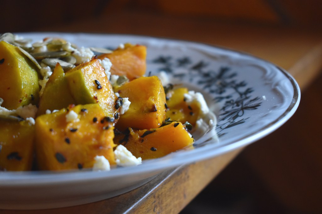 a plate of pumpkin pieces with cheese, nigella seeds and pumpkin seeds 