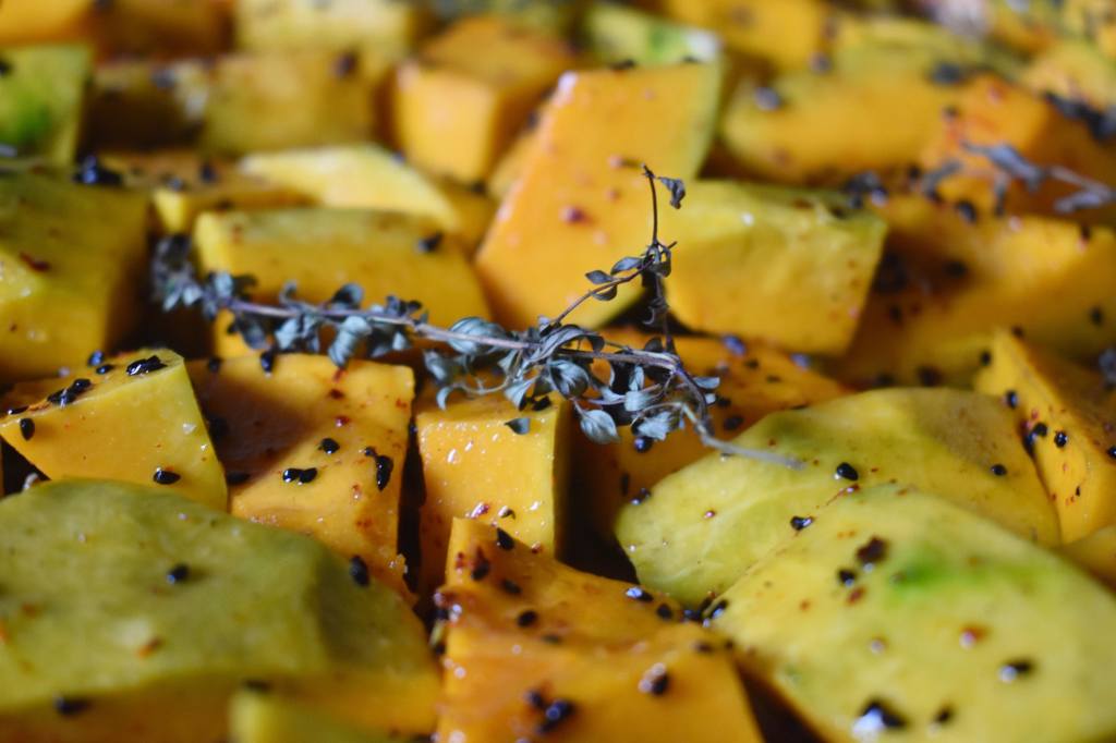 pieces of pumpkin covered with black seeds and a branch of dried herbs 
